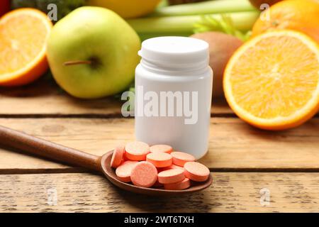 Compléments alimentaires. Bouteille, pilules à la cuillère et produits alimentaires sur table en bois Banque D'Images