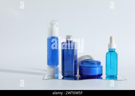Différents conteneurs avec des produits cosmétiques sur fond clair Banque D'Images