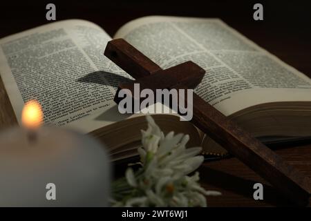 Croix, Bible, fleurs et bougie d'église sur table en bois Banque D'Images