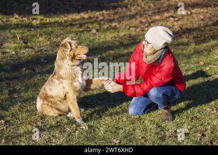 chien et femme assis dans l'herbe se regardant l'un l'autre, saison d'hiver Banque D'Images
