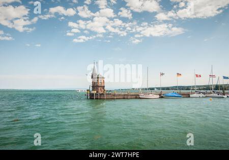 Vieux phare à la fin de la taupe de pierre dans le port de Constance. Peu de voiliers amarrés à la jetée. Belle vue sur le lac de Constance, ciel bleu à l'arrière. Banque D'Images