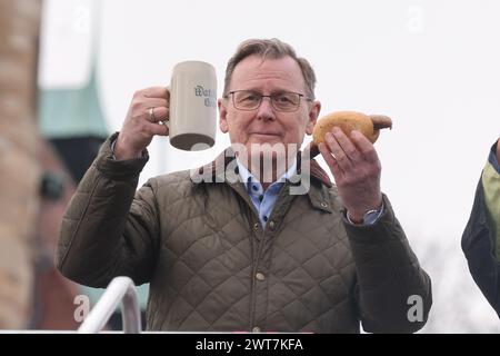 Erfurt, Allemagne. 16 mars 2024. Bodo Ramelow (Die Linke), ministre-président de Thuringe, tient une tasse de bière et une saucisse grillée à l'ouverture de la bratwurst avec le festival 'Rostkultur' sur la place de la cathédrale. Au total, onze types différents de Rostbratwurst peuvent être échantillonnés sur les stands. Crédit : Bodo Schackow/dpa/Alamy Live News Banque D'Images