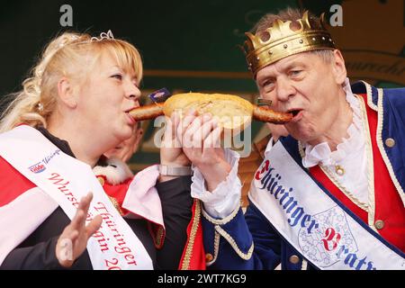 Erfurt, Allemagne. 16 mars 2024. Saucisse Queen Silvia (l) et Bratwurst King Norbert la première bouchée dans un Rostbratwurst à l'ouverture de la session de bratwurst avec le festival 'Rostkultur' sur la place de la cathédrale. Au total, onze types différents de Rostbratwurst peuvent être échantillonnés sur les stands. Crédit : Bodo Schackow/dpa/Alamy Live News Banque D'Images