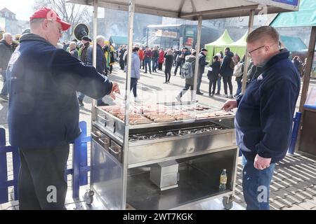 Erfurt, Allemagne. 16 mars 2024. Les saucisses de Rostbratwurst sont rôties sur un grill au charbon de bois sur la place de la cathédrale à l'ouverture de la session de bratwurst avec le festival 'Rostkultur'. Un total de onze types différents de saucisses grillées peuvent être échantillonnés sur les stands. Crédit : Bodo Schackow/dpa/Alamy Live News Banque D'Images