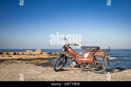 Un vieux scooter garé près de la mer à Borg Errass sur le Cap Afrique, Mahdia, Tunisie Banque D'Images