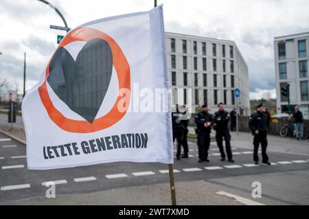 Regensburg, Allemagne. 16 mars 2024. Une bannière indique « dernière génération ». Les policiers se tiennent à l'arrière-plan. La dernière génération proteste contre la politique climatique du gouvernement des feux de signalisation. Crédit : Daniel Vogl/dpa/Alamy Live News Banque D'Images