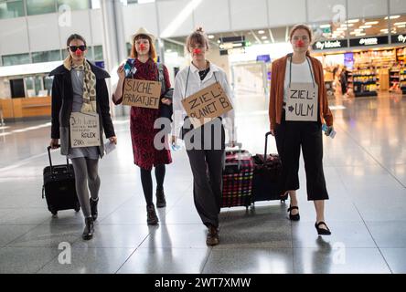 Stuttgart, Allemagne. 16 mars 2024. Les participants à une manifestation de la « dernière génération » protestent contre la politique climatique du gouvernement des feux de signalisation dans le terminal 3 de l'aéroport de Stuttgart, portant des pancartes indiquant « je ne peux pas voyager en train avec ma Rolex », « je cherche un jet privé », « destination planète B » et « destination : ULM ». Des démonstrations de dernière génération avec des médecins, des scientifiques, des commerçants, des étudiants et des retraités ont lieu dans toute l'Allemagne. Crédit : Christoph Schmidt/dpa/Alamy Live News Banque D'Images