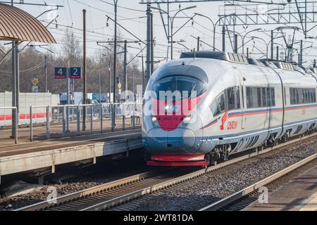 PETRO-SLAVYANKA, RUSSIE - 04 MARS 2024 : le train électrique à grande vitesse EVS1-16 'Sapsan' passe devant une station de banlieue un jour de mars. Oktyabrskaya Railway Banque D'Images