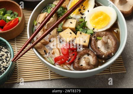 Bol de délicieux ramen et ingrédients sur la table grise, gros plan. Soupe de nouilles Banque D'Images