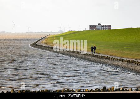 Husum, Allemagne. 16 mars 2024. Un homme et une femme marchent le long d'une digue sur la mer du Nord au soleil. Crédit : Frank Molter/dpa/Alamy Live News Banque D'Images