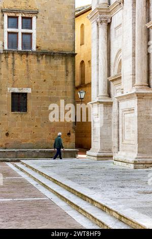 Un homme passe par la cathédrale de Pienza, une ville médiévale en Toscane, pleine de vieilles maisons et structures, également déclarée site du patrimoine de l'UNESCO. Banque D'Images