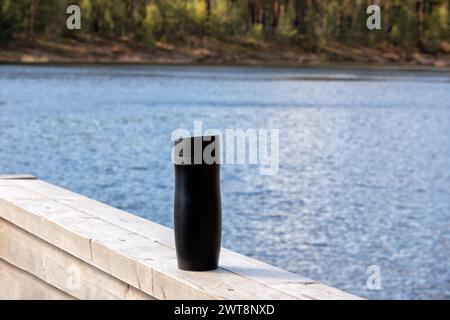 Thermos noirs sur planche de bois avec fond d'eau bleu Banque D'Images