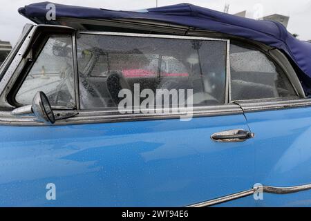 Fenêtre de voiture décapotable classique américaine 079 et détail de capote -bleu Chevrolet 1950- stationné sous la pluie sur Revolution Square. La Havane-Cuba. Banque D'Images
