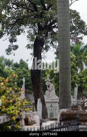 089 statue en marbre d'une jeune femme gentille agenouillée tout en serrant une croix au sommet d'une tombe imposante dans le cimetière Cementerio Cristobal Colon. La Havane-Cuba. Banque D'Images