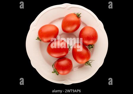 Plusieurs tomates cocktail sur une plaque de céramique blanche sur fond noir, macro, vue de dessus. Banque D'Images