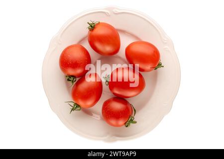 Plusieurs tomates cocktail sur une plaque de céramique blanche sur fond blanc, macro, vue de dessus. Banque D'Images