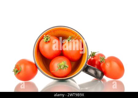 Plusieurs tomates cocktail mûres avec tasse en céramique, macro, isolées sur fond blanc. Banque D'Images