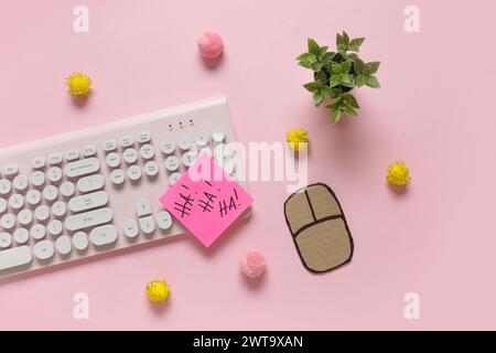 Clavier d'ordinateur avec souris de carton, note collante et décor sur fond rose. Farce du jour des fous d'avril Banque D'Images