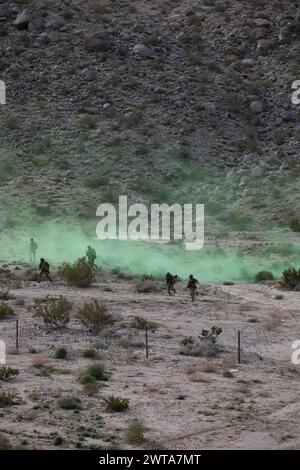 Les parachutistes de l'armée américaine affectés à la compagnie Bravo, 2nd Battalion, 508th Parachute Infantry Regiment, 2nd Brigade combat Team, 82nd Airborne Division se déplacent rapidement vers leur objectif sous dissimulation en tirant parti d'un petit transport d'équipement polyvalent de l'armée américaine lors d'une expérience d'intégration de machines humaines pendant le projet convergence Capstone 4 à Fort Irwin, Calif., 11 mars 2024. Un SMET est un robot à huit roues, permettant la technologie robotique servant de 'mule robotique' avec une large gamme de flexibilité pour fonctionner dans les opérations de combat. PC-C4 est une expérience interarmées et multinationale hébergée par l'armée américaine Banque D'Images