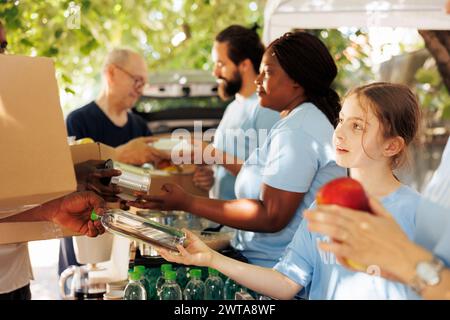 Groupe caritatif, comprenant des hommes et des femmes de différents âges et ethnies, fournissant ensemble des dons et du soutien pour la collecte de nourriture. Les bénévoles distribuent des conserves et des articles essentiels aux nécessiteux. Banque D'Images