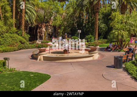 Vue sur les gens qui se promènent dans le jardin tropical du casino Flamingo Hotel, surplombant une fontaine et des sculptures de flamants roses. Las Vegas. Banque D'Images