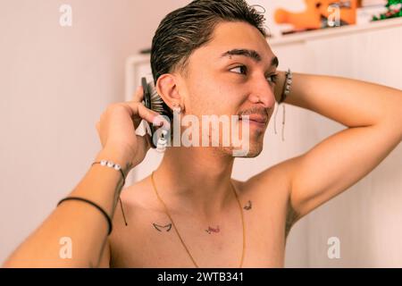 Un jeune homme latino souriant et coiffant avec confiance ses cheveux, mettant en valeur un charme décontracté Banque D'Images