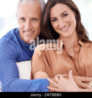 Couple, différence d'âge et câlin en portrait, amour avec une relation unique et soutien pour la confiance à la maison. Homme âgé, jeune femme mariée Banque D'Images