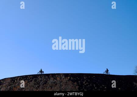 Silhouette de cyclistes sur le bord d'un cratère dans le parc de l'Etna, Sicile, Italie Banque D'Images