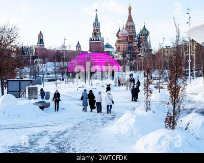 Moscou, Russie - 8 février 2024 : visiteurs sur un chemin enneigé dans le parc public de la ville de Zaryadye et vue sur la cathédrale Saint-Basile et les tours du Kremlin au M. Banque D'Images