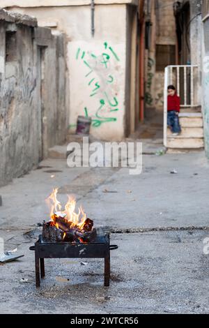 Bilin, Ramallah, Palestine. 22 décembre 2010. Une jeune fille palestinienne regarde le feu dans une rue du camp d'Amari près de Ramallah, Cisjordanie, Palestine, le 22 décembre 2010. Le camp d’Amari est l’un des nombreux camps de réfugiés créés après que les Juifs eurent pris possession d’une grande partie de l’espace de vie palestinien lors de la création d’Israël en 1948. De nouvelles générations de Palestiniens vivent encore dans ces camps. Bilin, un petit village près de Ramallah, organise des manifestations hebdomadaires car une grande partie des terres des agriculteurs locaux a été annexée par les autorités israéliennes pour construire une nouvelle colonie juive. (Crédit image : © Dominika Zarzycka/SOPA images via ZUMA Press Wire) EDITORIAL USA Banque D'Images