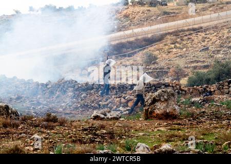 Bilin, Ramallah, Palestine. 31 décembre 2010. Des activistes palestiniens marchent avec des sacs en plastique sur la tête dans un nuage de gaz lors des manifestations hebdomadaires du vendredi contre l’occupation des territoires palestiniens par Israël à Bilin, Cisjordanie, Palestine, le 31 décembre 2010. Bilin, un petit village près de Ramallah, organise des manifestations hebdomadaires car une grande partie des terres des agriculteurs locaux a été annexée par les autorités israéliennes pour construire une nouvelle colonie juive. (Crédit image : © Dominika Zarzycka/SOPA images via ZUMA Press Wire) USAGE ÉDITORIAL SEULEMENT! Non destiné à UN USAGE commercial ! Banque D'Images