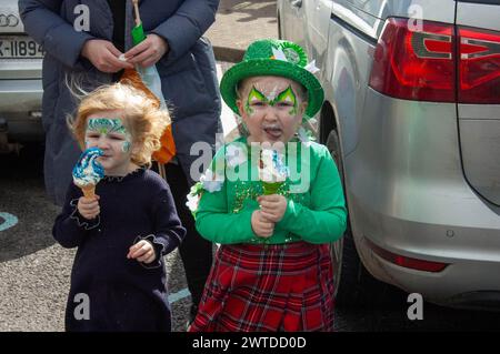 Dimanche 17 mars 2024 Bantry West Cork, Irlande ; Bantry a tenu sa réunion Défilé de la fête de Patrick aujourd’hui. Plus de 20 chars provenant d’écoles, de clubs et d’entreprises locales ont participé avec Florrie O’Driscoll en tant que Grand Marshall et dirigé par Ballingeary Pipe Band. Plus de 200 personnes se sont rendues pour regarder la parade qui a été MC'd par Gearoid O'Leary. Pepper et Robin Attwell de Glengarriff enjioying Ice Cream et regardent leur père diriger la parade avec le Ballingeary Pipe Band. Credit ED/Alamy Live News Banque D'Images