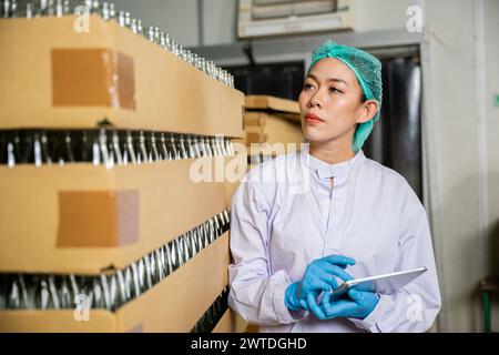 QC Woman utilise une tablette numérique pour vérifier les produits sur la bande transporteuse Banque D'Images