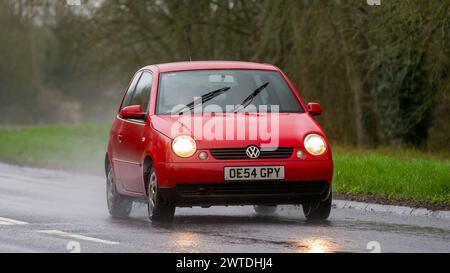 Milton Keynes, UK-Mar 17th 2024 : 2004 voiture rouge Volkswagen Lupo conduisant sous la pluie Banque D'Images