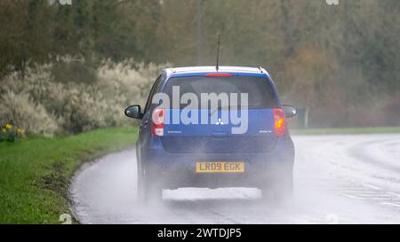 Milton Keynes, UK-Mar 17th 2024 : 2009 bleu Mitsubishi Colt voiture conduisant sous la pluie Banque D'Images