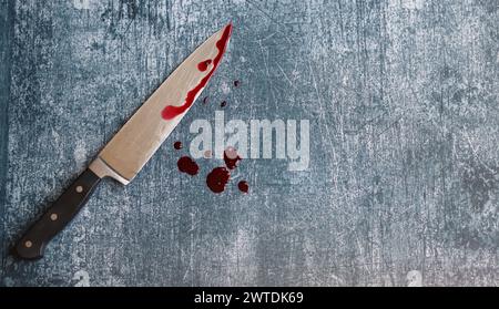 Gros couteau sanglant sur fond gris grungy avec espace de copie. Gouttes de sang sur fond rouillé. Concept de violence domestique. Banque D'Images