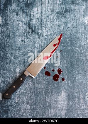 Gros couteau sanglant sur fond gris grungy avec espace de copie. Gouttes de sang sur fond rouillé. Concept de violence domestique. Banque D'Images
