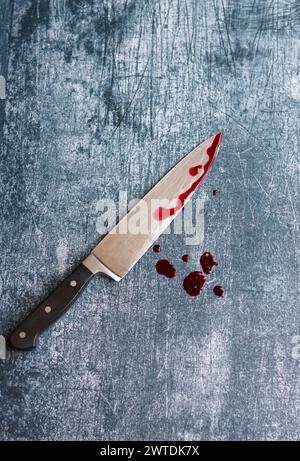Gros couteau sanglant sur fond gris grungy avec espace de copie. Gouttes de sang sur fond rouillé. Concept de violence domestique. Banque D'Images