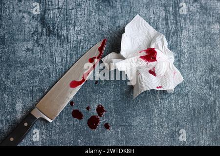 Gros couteau sanglant sur fond gris grungy avec espace de copie. Gouttes de sang sur fond rouillé. Concept de violence domestique. Banque D'Images