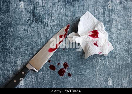 Gros couteau sanglant sur fond gris grungy avec espace de copie. Gouttes de sang sur fond rouillé. Concept de violence domestique. Banque D'Images