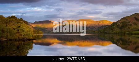 En regardant Ullswater alors que la première lumière du jour atteint les sommets de Heron Pike et Sheffield Pike. Banque D'Images