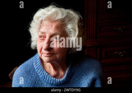 Portrait d'une vieille femme à la maison, levant les yeux. Banque D'Images