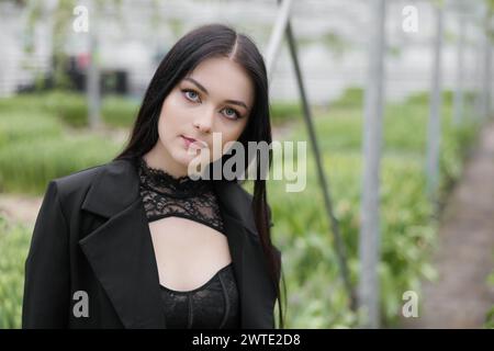 Jeune femme debout dans une grande serre avec des tulipes. Banque D'Images