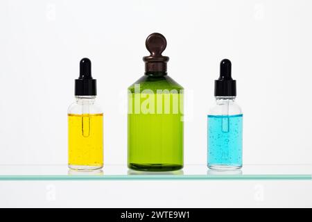 Gros plan des flacons compte-gouttes. Sérum facial coloré, huile essentielle sur fond blanc. Concept de traitement de beauté, liquide tonique vert visage. Cosme aromatique Banque D'Images