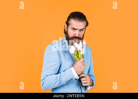 beau homme d'affaires caucasien avec la coiffure tendance en veste avec des fleurs de tulipe, cadeau Banque D'Images