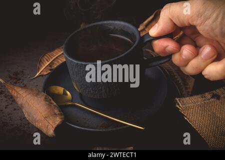 Tasse de café avec des feuilles d'automne sur un fond noir, ton vintage Banque D'Images