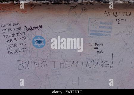 Abbey Road, Londres, Royaume-Uni. 17 mars 2024. Un groupe de lycéens israéliens, survivants de l'attaque terroriste du 7 octobre 2023, qui se rendaient à Londres dans le cadre d’une délégation organisée par le projet 7/10 Human Chain, écrivent des messages sur le mur des studios d’Abbey Road pour leurs 7 amis et voisins, toujours détenus en captivité à Gaza depuis qu’ils ont été enlevés de chez eux lors d’une attaque palestinienne en Israël il y a 163 jours. Le groupe a rendu visite à des étudiants à Londres pour partager leurs histoires et expériences horribles du massacre. Photo par Amanda Rose/Alamy Live News Banque D'Images