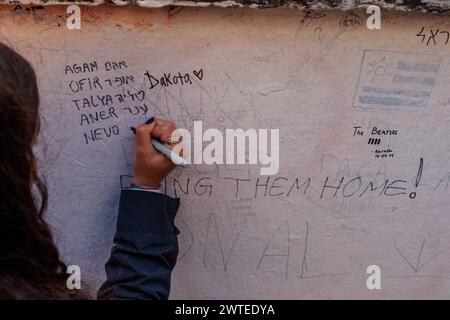 Abbey Road, Londres, Royaume-Uni. 17 mars 2024. Un groupe de lycéens israéliens, survivants de l'attaque terroriste du 7 octobre 2023, qui se rendaient à Londres dans le cadre d’une délégation organisée par le projet 7/10 Human Chain, écrivent des messages sur le mur des studios d’Abbey Road pour leurs 7 amis et voisins, toujours détenus en captivité à Gaza depuis qu’ils ont été enlevés de chez eux lors d’une attaque palestinienne en Israël il y a 163 jours. Le groupe a rendu visite à des étudiants à Londres pour partager leurs histoires et expériences horribles du massacre. Photo par Amanda Rose/Alamy Live News Banque D'Images