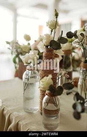 Plusieurs vases remplis d'un assortiment de fleurs colorées reposent sur une table en bois. Banque D'Images