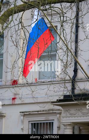 Londres, Royaume-Uni. 17 mars 2024. Le drapeau russe flotte devant l'ambassade à Kensington, à côté des éclaboussures de peinture rouge. Des milliers d'électeurs sont descendus à l'ambassade de Russie à Kensington et certains d'entre eux ont fait la queue pendant quatre heures avant de voter. Beaucoup d'attente ont été vues drapées dans le drapeau bleu et blanc pro-démocratie alors que Yulia, l'épouse du défunt leader de l'opposition Alexei Navalny, a exhorté les électeurs à se présenter à une manifestation "midi contre Poutine", tandis que l'équipe de Navalny a demandé aux individus de gâcher leurs bulletins de vote. Crédit : onzième heure photographie/Alamy Live News Banque D'Images